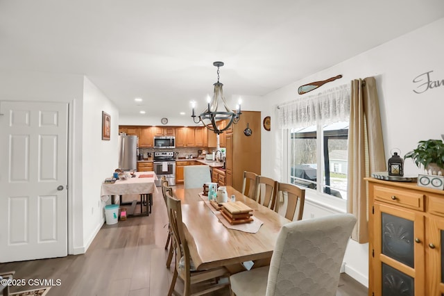 dining space featuring light wood-type flooring, sink, and an inviting chandelier