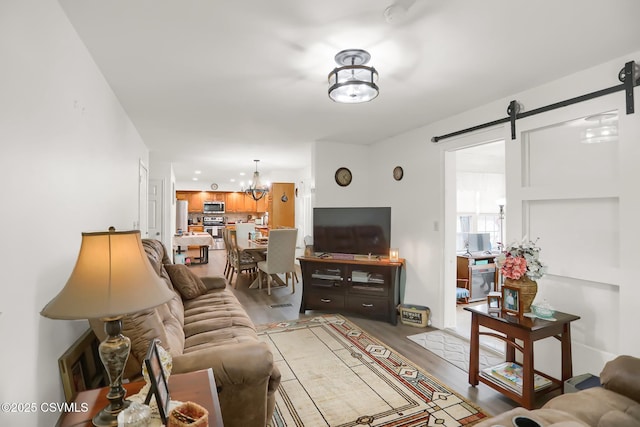 living room featuring a barn door, a notable chandelier, and light hardwood / wood-style floors