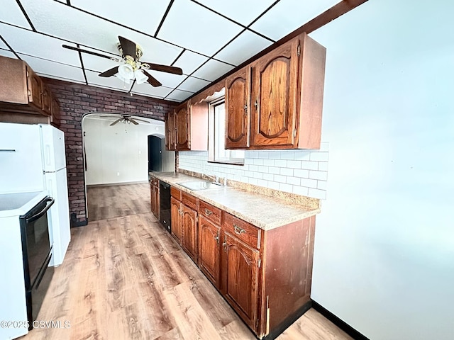 kitchen with black appliances, a paneled ceiling, backsplash, light wood-type flooring, and ceiling fan