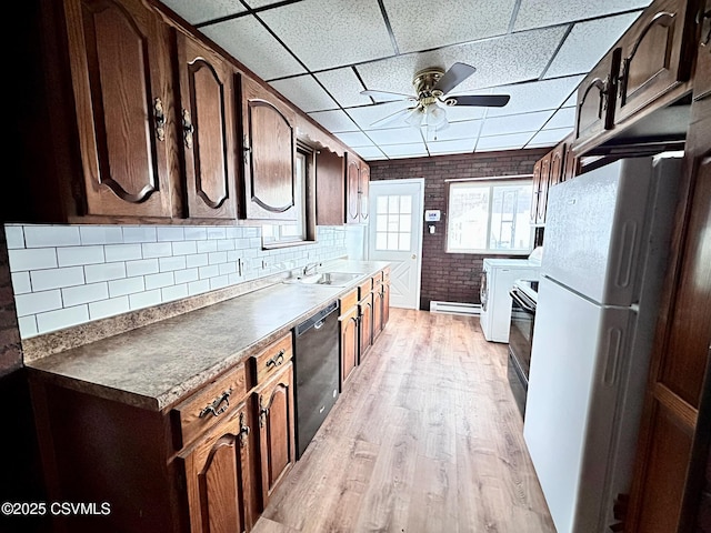 kitchen with black appliances, sink, light wood-type flooring, a paneled ceiling, and brick wall