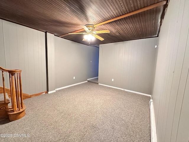 basement featuring ceiling fan, carpet flooring, wooden walls, and wooden ceiling