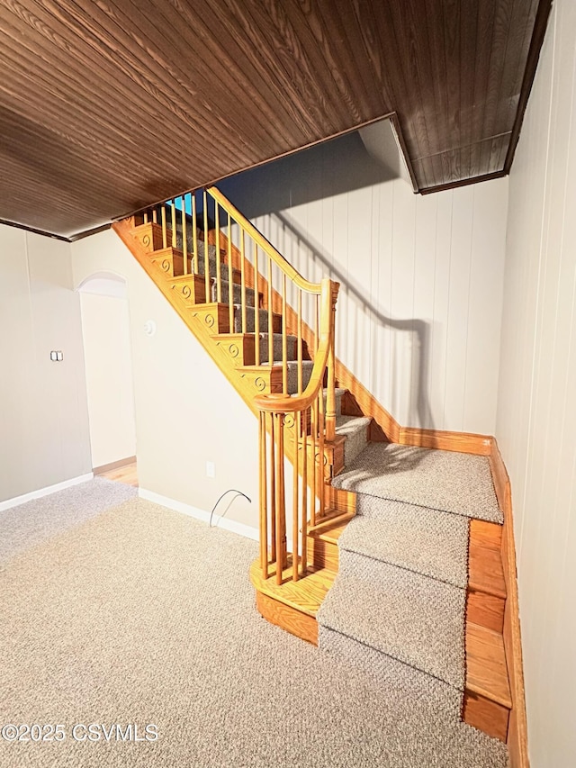 stairway with carpet, wood walls, and wood ceiling