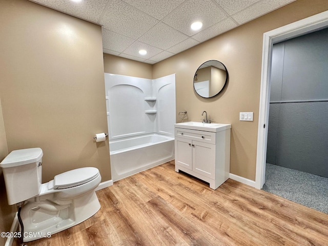 full bathroom featuring toilet, vanity, a drop ceiling, shower / washtub combination, and hardwood / wood-style floors