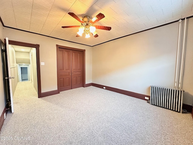 unfurnished bedroom featuring ceiling fan, radiator, crown molding, and carpet flooring