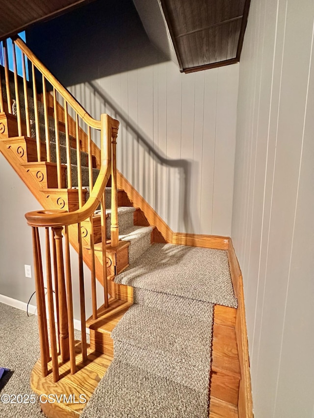 stairway featuring carpet and wooden walls