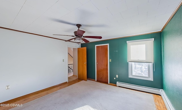 spare room with crown molding, hardwood / wood-style floors, ceiling fan, and baseboard heating