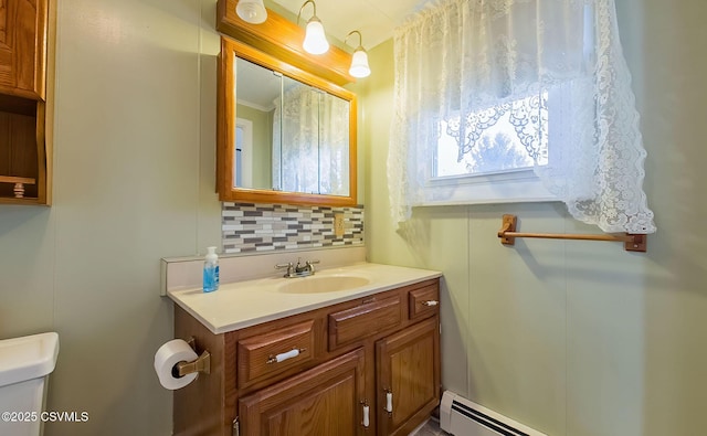 bathroom featuring vanity, a baseboard heating unit, backsplash, and toilet