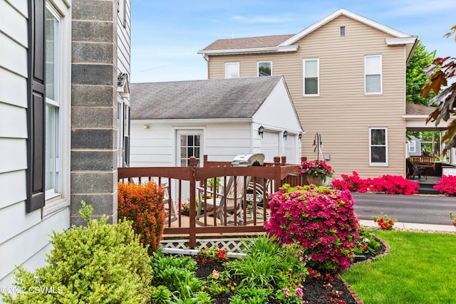 rear view of property featuring a wooden deck and a garage