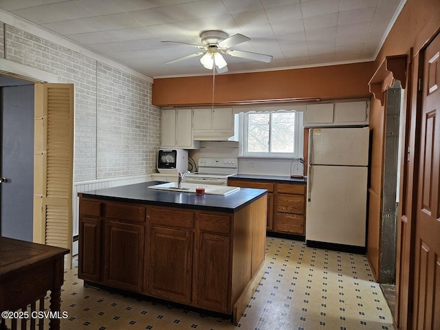 kitchen with brick wall, white appliances, ornamental molding, a kitchen island with sink, and ceiling fan