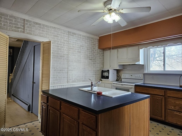 kitchen with brick wall, a baseboard heating unit, electric stove, a center island with sink, and crown molding