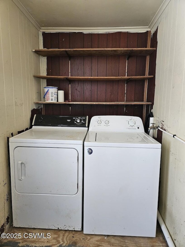 clothes washing area featuring washer and dryer, crown molding, and wood walls