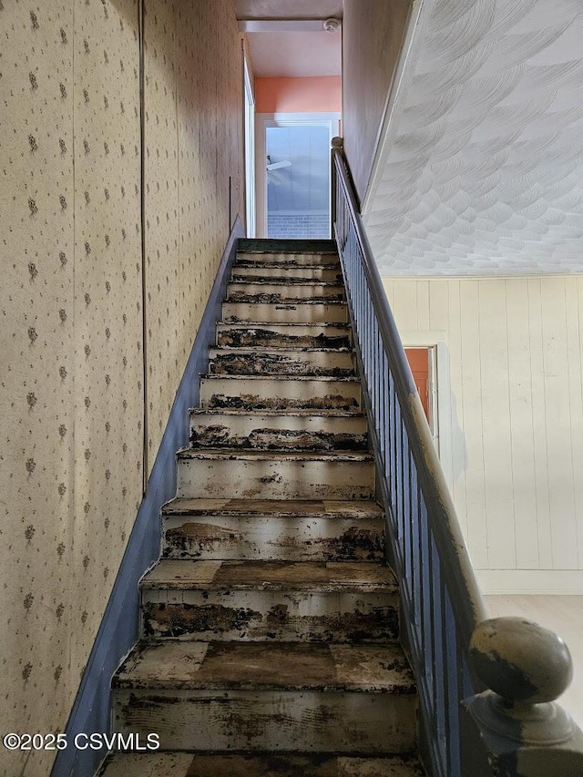 staircase featuring wood walls