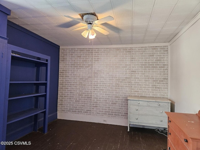 unfurnished bedroom with ceiling fan, brick wall, and dark hardwood / wood-style flooring