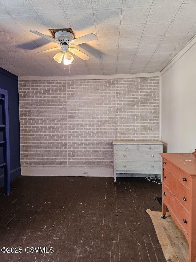 unfurnished bedroom featuring ceiling fan, brick wall, and crown molding