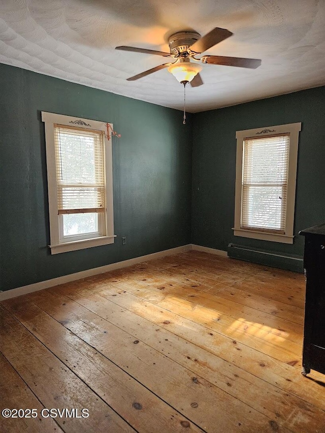 spare room featuring ceiling fan, wood-type flooring, and baseboard heating