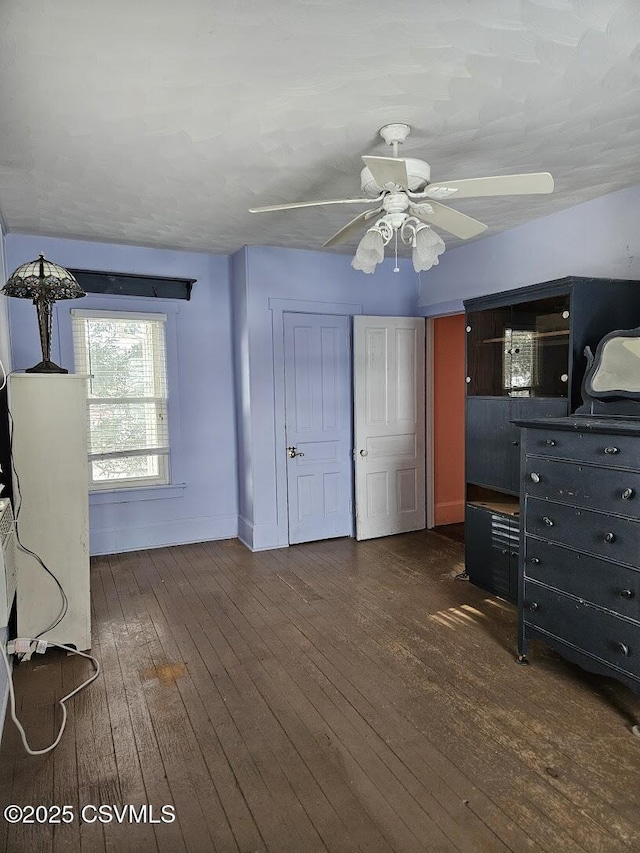 unfurnished bedroom with ceiling fan and dark hardwood / wood-style floors