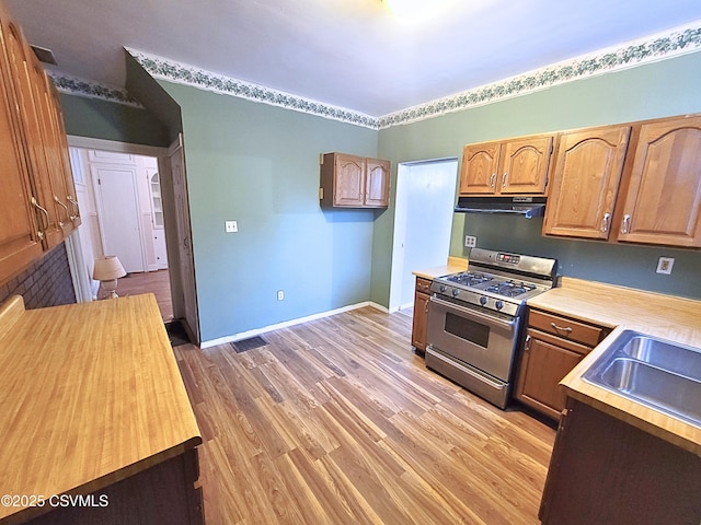 kitchen featuring sink, wooden counters, light hardwood / wood-style flooring, and stainless steel range with gas cooktop