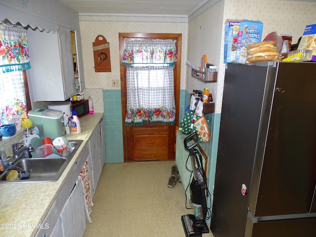 kitchen with sink, ornamental molding, and stainless steel refrigerator