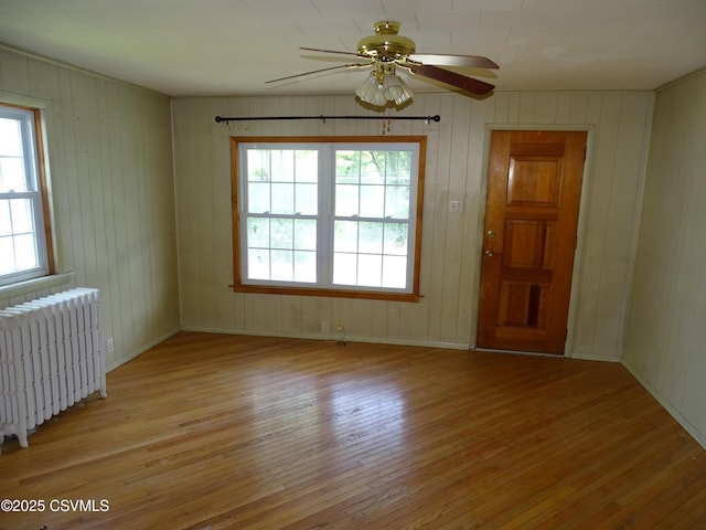263 State Route 2026, Coal Township, PA 17866 - spare room featuring radiator heating unit, light wood-style flooring, plenty of natural light, ceiling fan, and wood walls