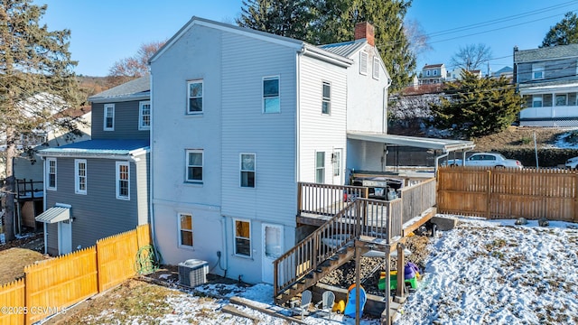 snow covered house with cooling unit and a deck