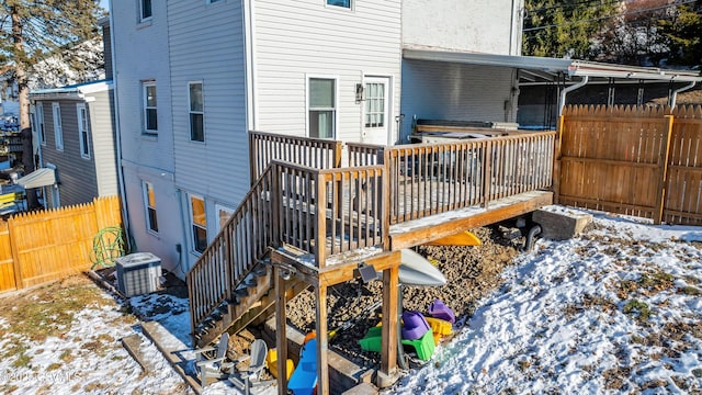 snow covered house with a wooden deck and central air condition unit