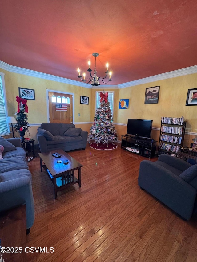 living room with wood-type flooring, ornamental molding, and a chandelier