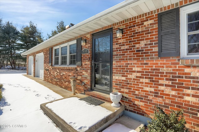 snow covered property entrance featuring a garage