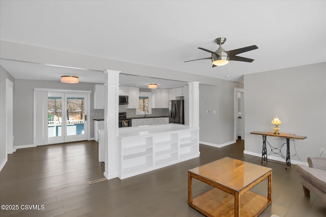 living room featuring ornate columns, dark hardwood / wood-style floors, and ceiling fan