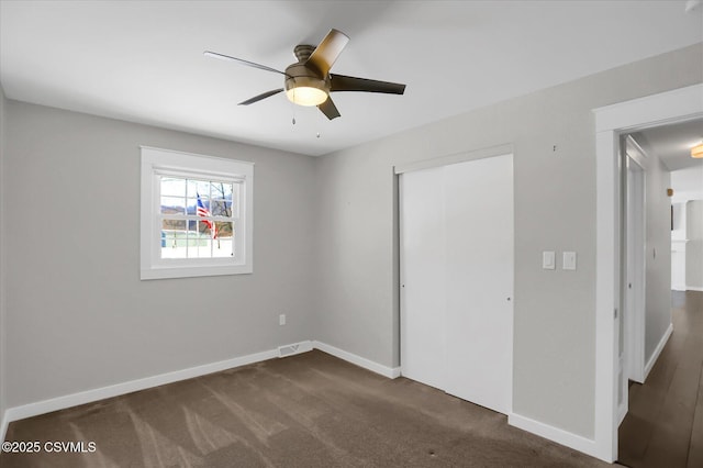 unfurnished bedroom featuring dark colored carpet, ceiling fan, and a closet