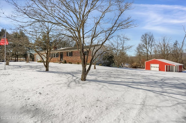 yard covered in snow featuring an outbuilding and a garage