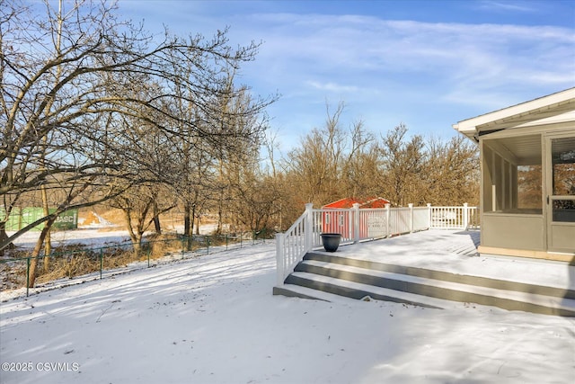 snowy yard featuring a wooden deck and a sunroom