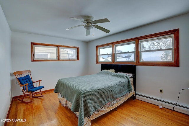 bedroom featuring a baseboard heating unit, ceiling fan, and light hardwood / wood-style floors