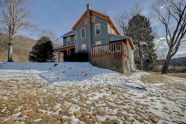 snow covered rear of property with a deck