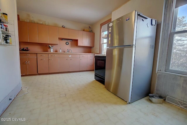 kitchen with black range with electric cooktop, stainless steel fridge, and sink