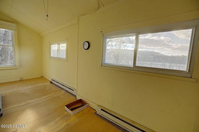 spare room featuring baseboard heating, a healthy amount of sunlight, and lofted ceiling