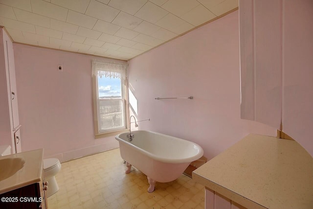 bathroom featuring vanity, a tub to relax in, and toilet