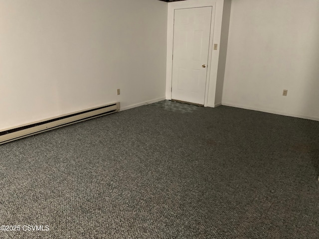 empty room featuring a baseboard heating unit and dark carpet