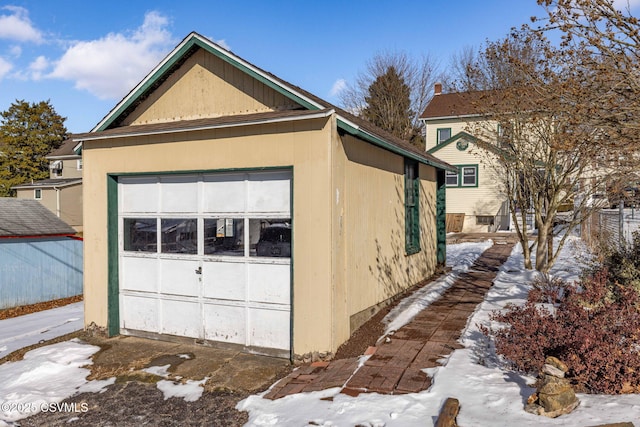 snow covered property featuring a garage and an outdoor structure