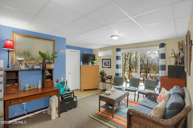 living room featuring a paneled ceiling, carpet flooring, and an AC wall unit