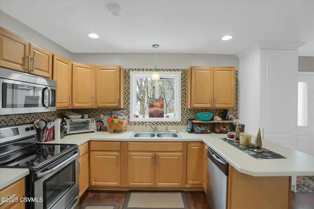 kitchen with appliances with stainless steel finishes, decorative light fixtures, sink, backsplash, and kitchen peninsula