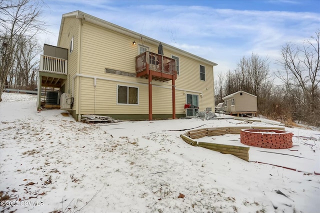 snow covered back of property featuring a balcony