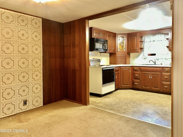 kitchen featuring white electric range, wooden walls, sink, and light carpet