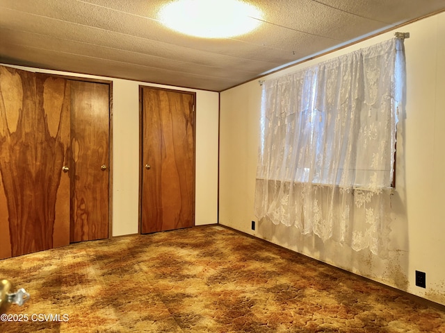 unfurnished bedroom featuring carpet flooring and two closets