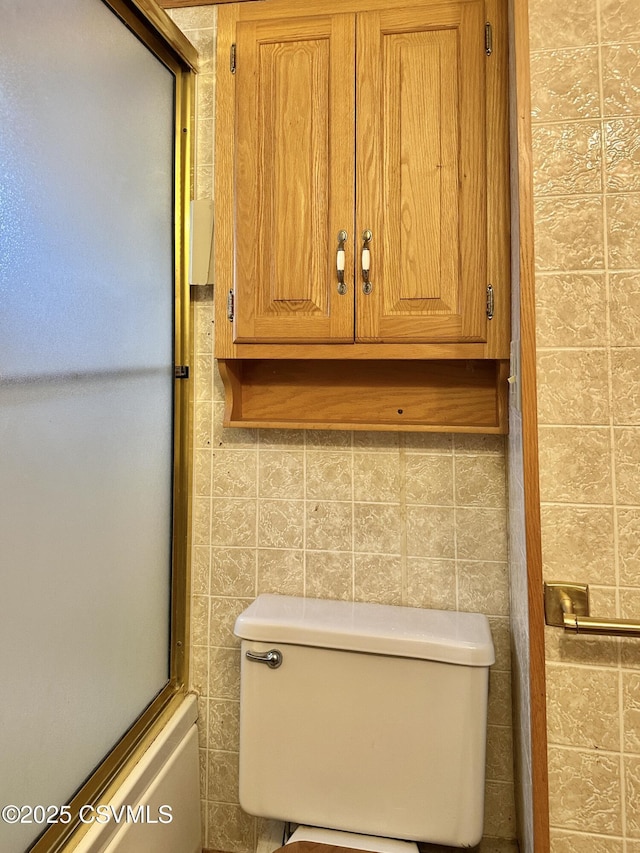 bathroom with decorative backsplash, bath / shower combo with glass door, and toilet