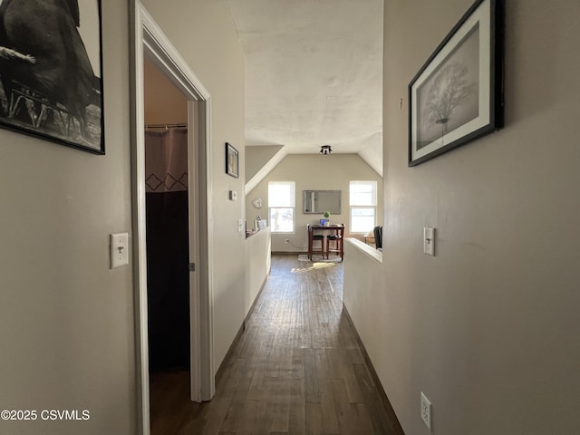 corridor with vaulted ceiling and hardwood / wood-style floors