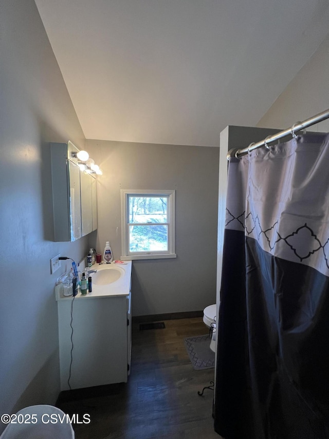 bathroom with lofted ceiling, hardwood / wood-style flooring, vanity, toilet, and a shower with curtain