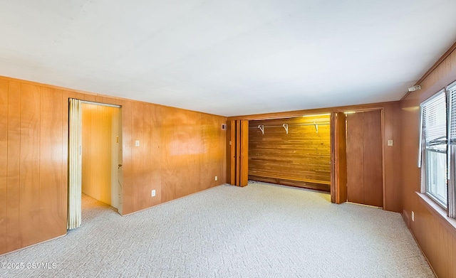 unfurnished bedroom with light carpet and wood walls