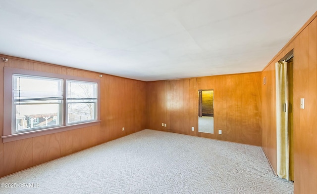 carpeted spare room with wooden walls