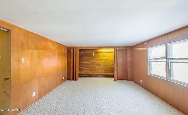 empty room with light colored carpet and wooden walls