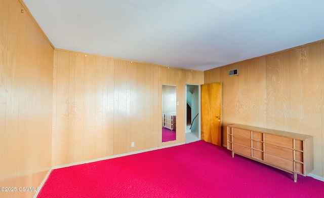 spare room featuring carpet floors and wood walls